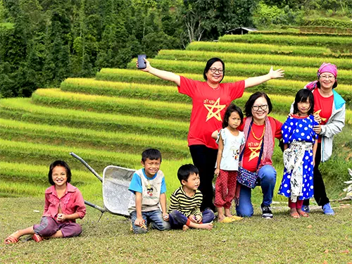 Du khách chụp ảnh cùng trẻ em người Dao tại xã Hồ Thầu dưới chân Chiêu Lầu Thi