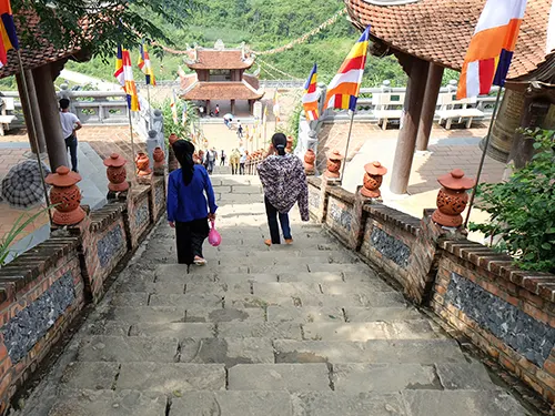 Du khách leo bậc đá lên chùa Phật Tích Trúc Lâm Bản Giốc, hai bên treo cờ Phật giáo
