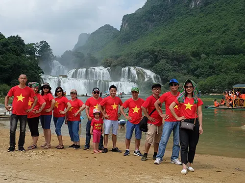 Đoàn khách Etoco mặc áo cờ đỏ sao vàng trước thác Bản Giốc trong tour Cao Bằng 2 ngày 1 đêm